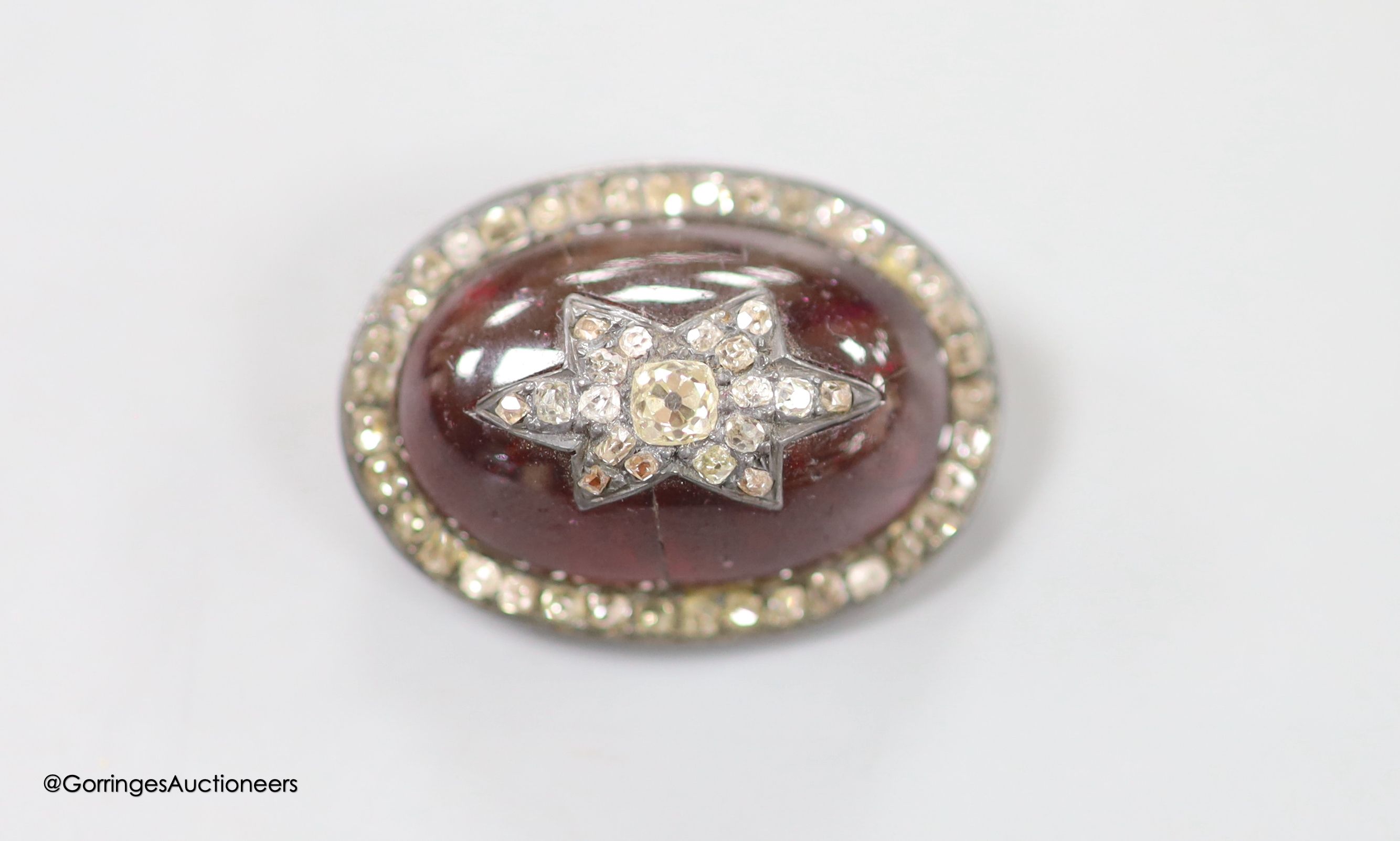 A 19th century yellow and white metal, oval cabochon garnet, rose and old cut diamond set brooch(adapted and stone cracked), with central star motif, 34mm, gross weight 15.9 grams.